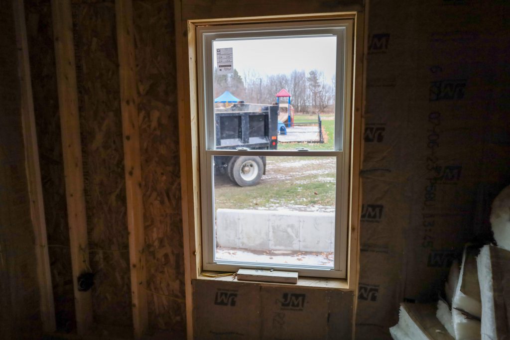 a view within the modular home, looking out the window, out the window you see a playground and a backside of a dump truck