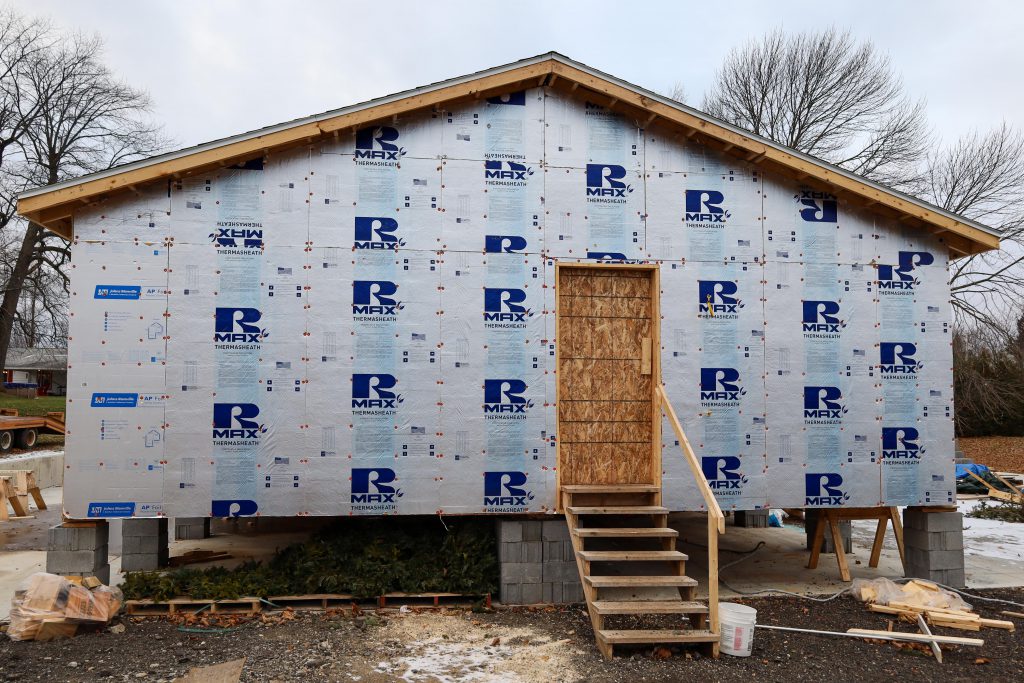 student built modular home, view from the back, shows stairs leading to where a door will go