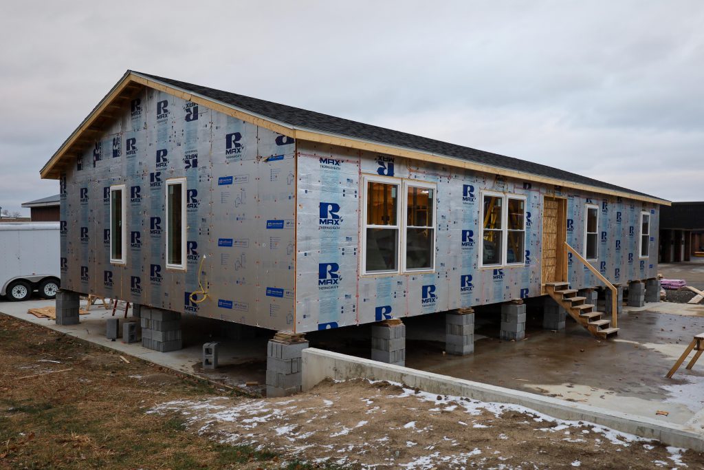 student built modular home. exertior view. siding has not been added, you see windows and stairs leading to where a door will go. modular home is on cement blocks to be able to transport