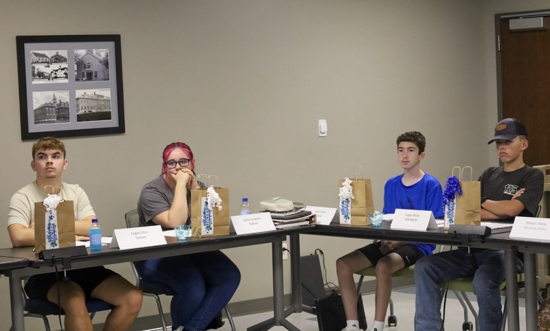 4 students sat and listening to someone off camera.