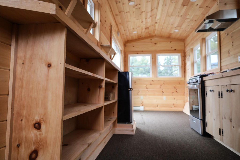 lower angle view from the kitchen facing toward front of the tiny house, another view of the kitchen to sliding door entrance