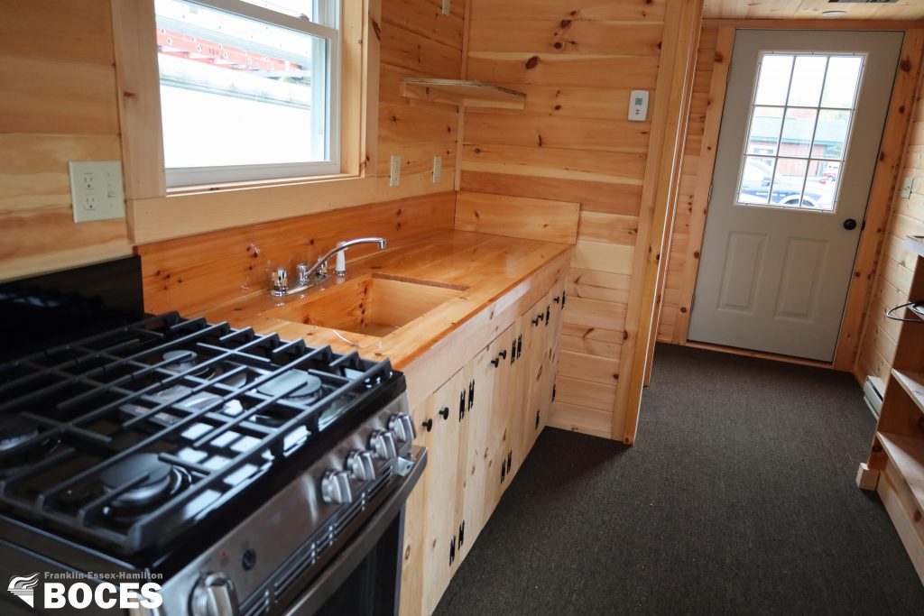 another view of the tiny house kitchen area, all pine interior, carpeted floor