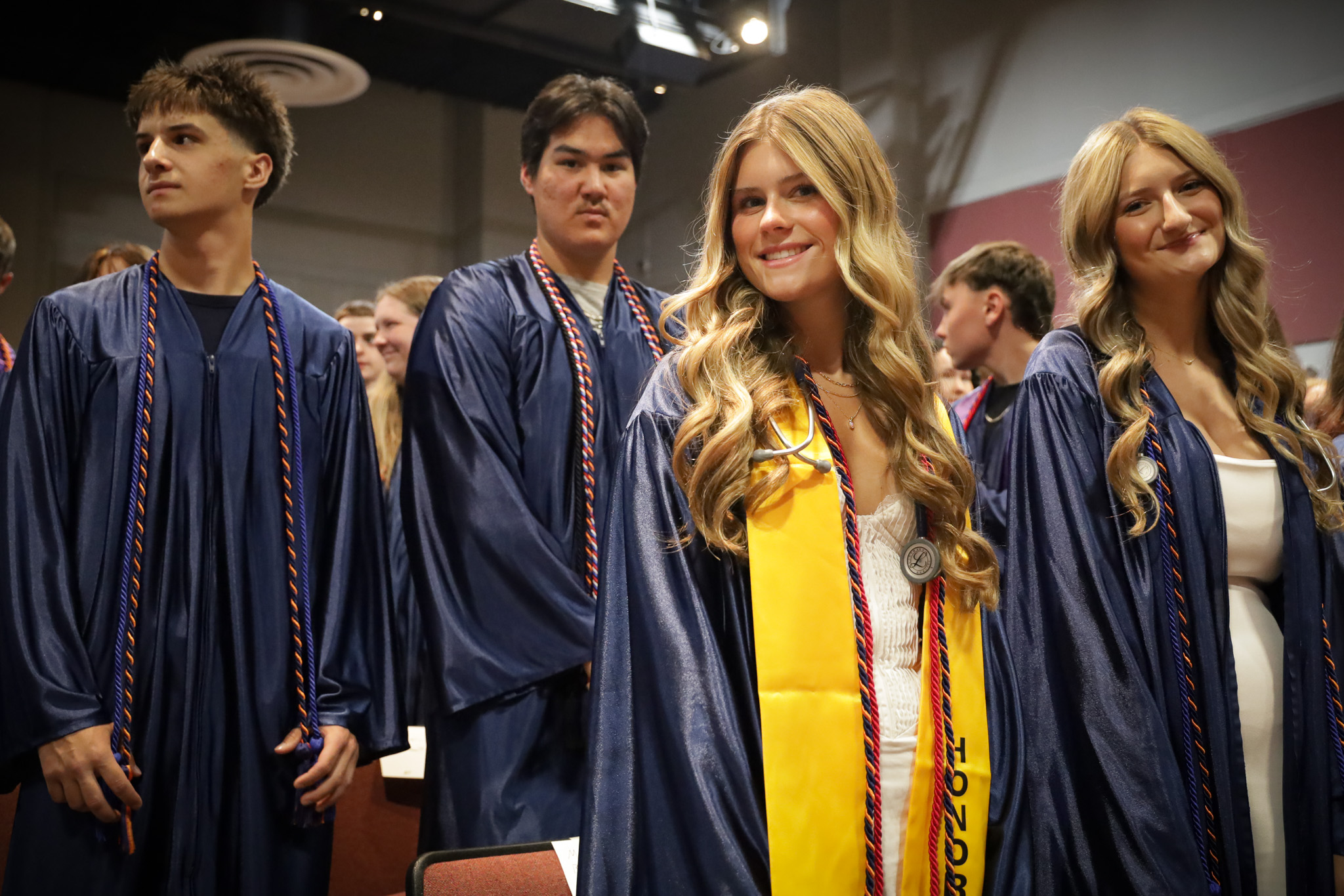 Graduates at ceremony standing smiling at camera