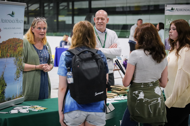 adults engaged in conversation with 3 students.