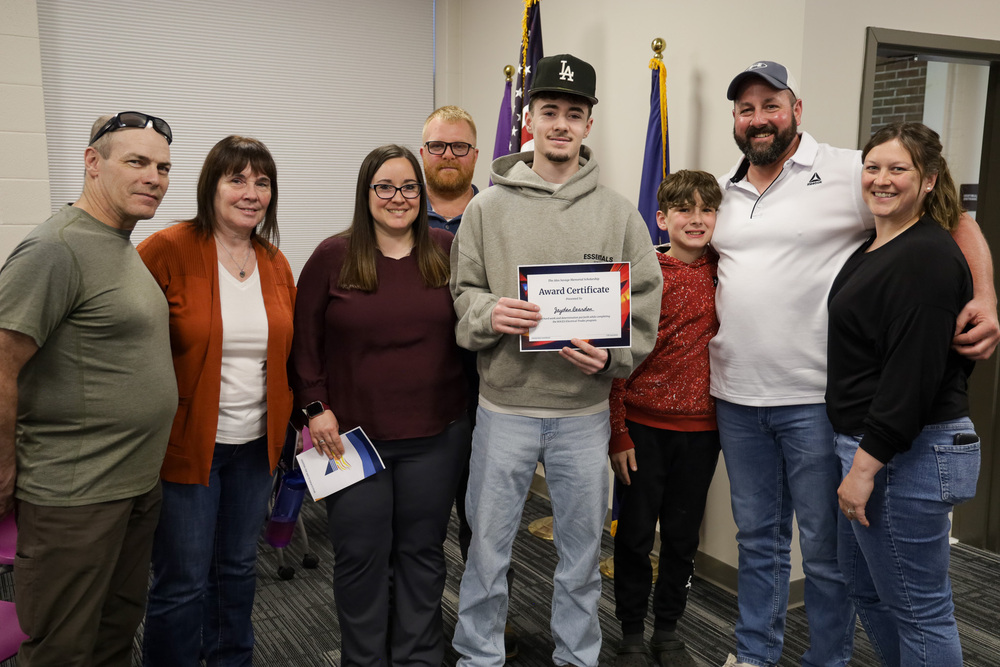 Student holding an award certificate with a happy family.