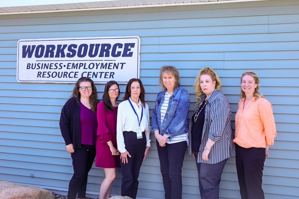 6 women standing together infront of a worksource sign.